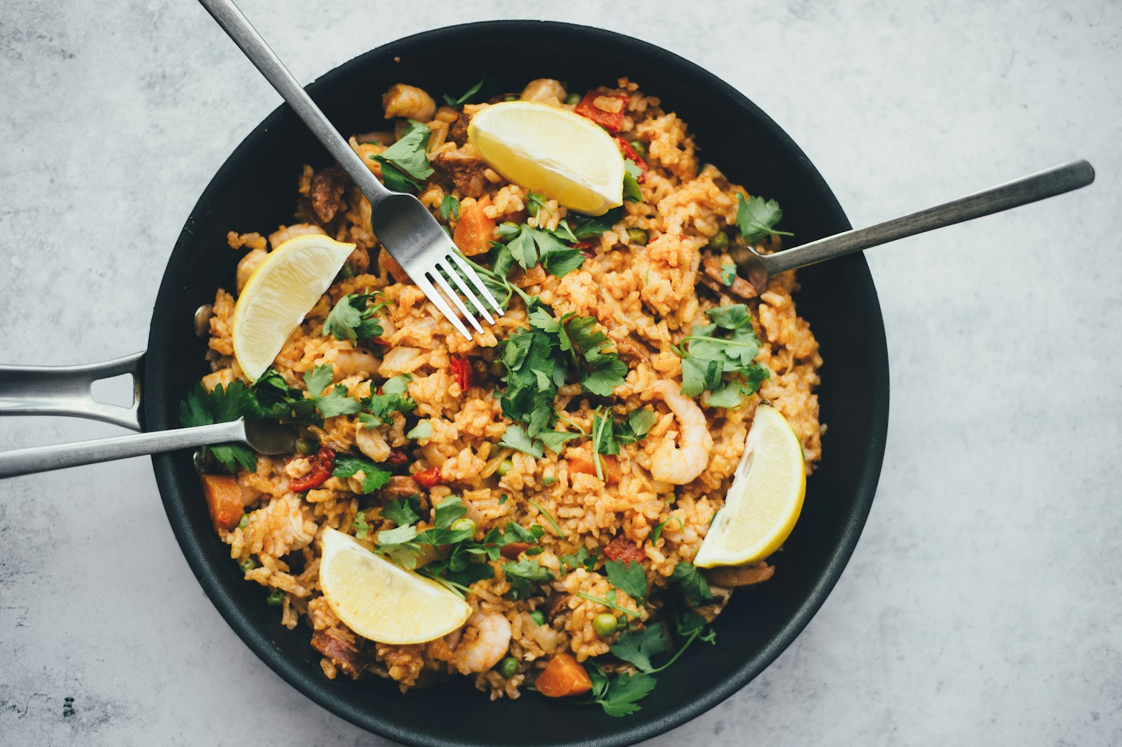 Orzo salad with basil leaves, lemon zest and cherry tomatoes in a serving bowl