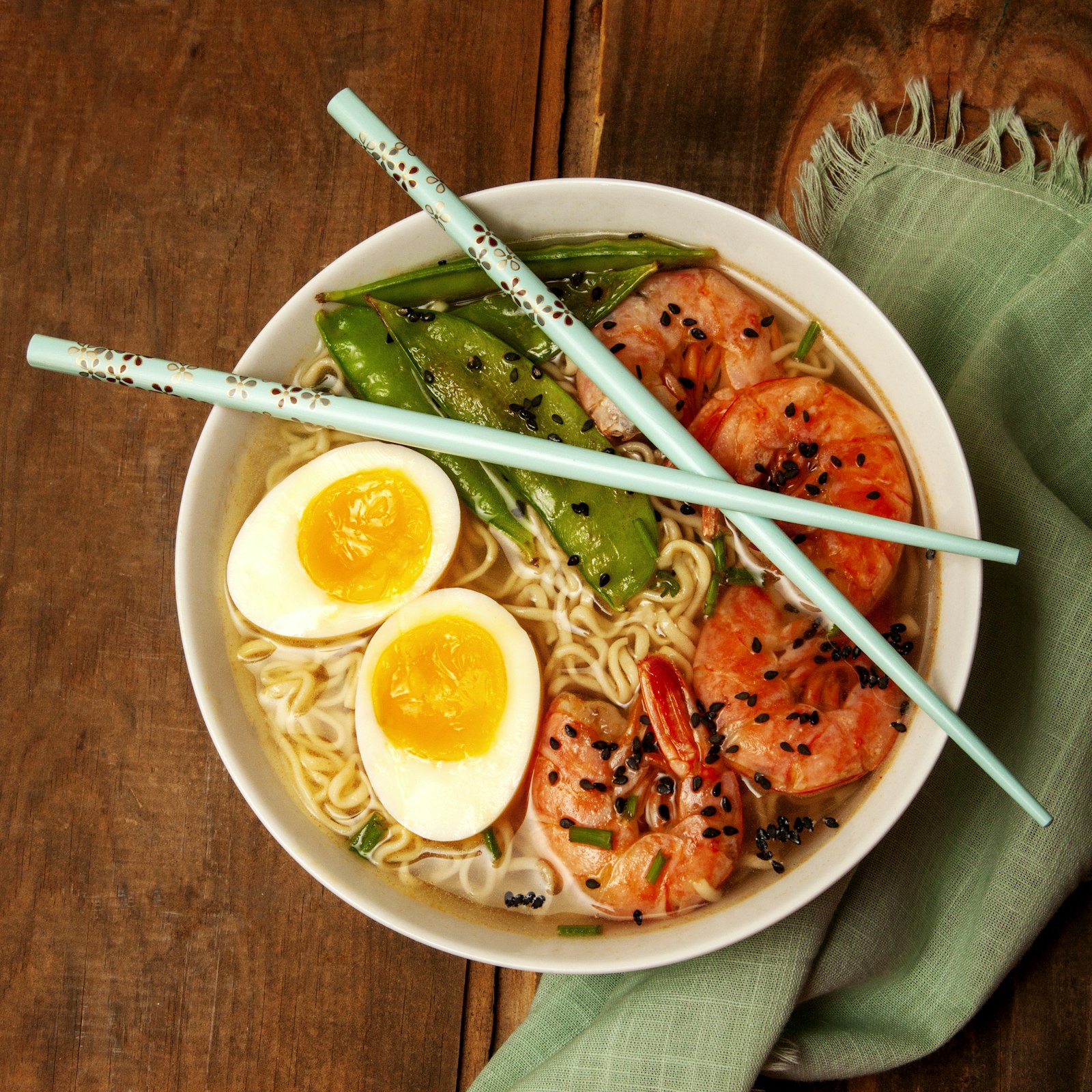 Tangle of sesame noodles in a shallow bowl topped with sliced scallions and chilli crisp