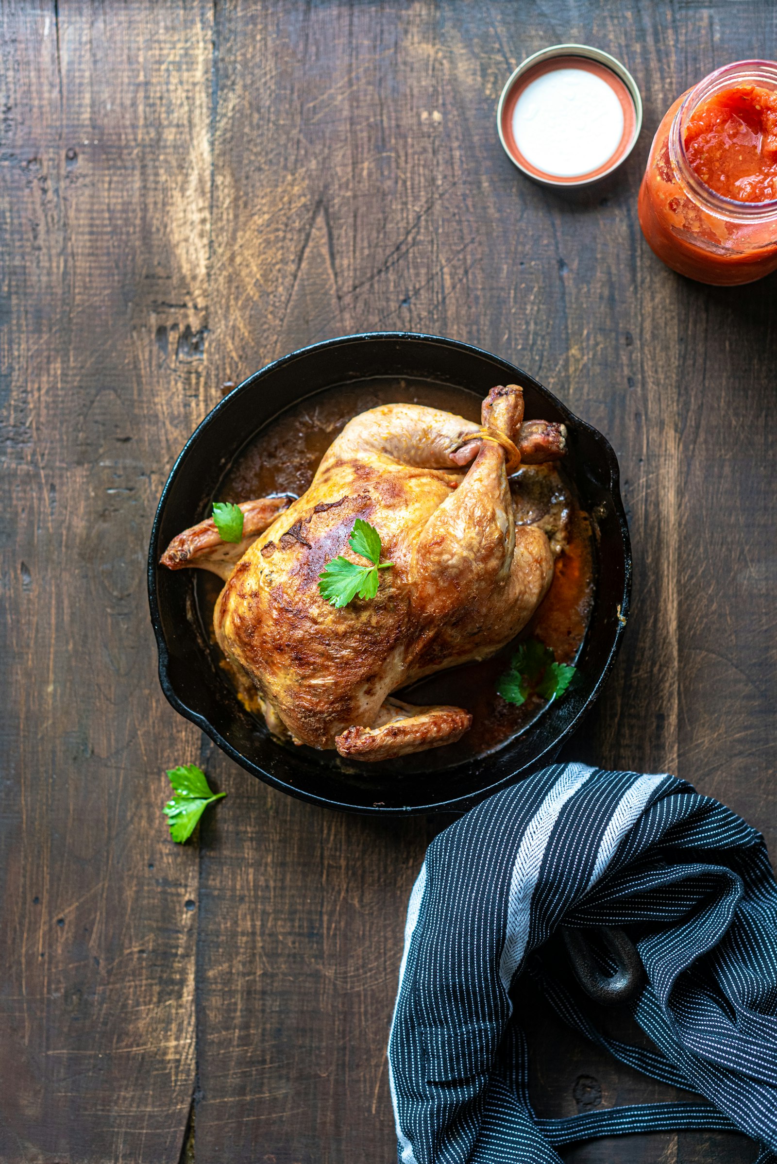 Golden herb butter roast chicken resting in a roasting pan with lemon halves
